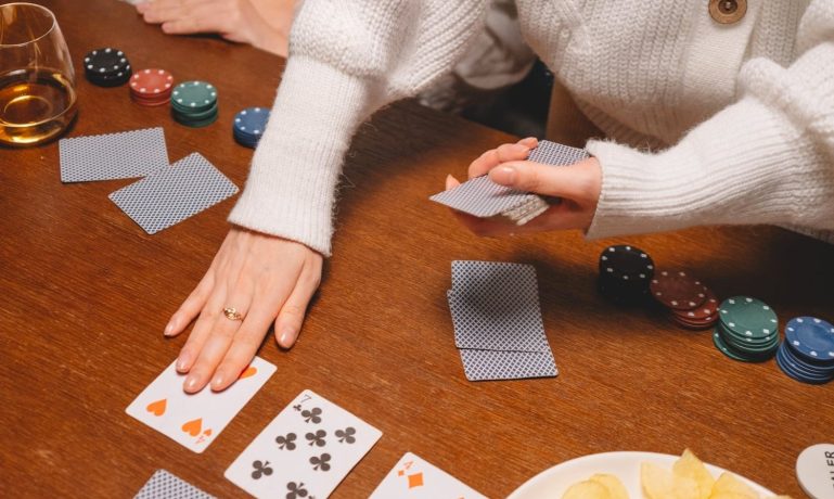 Foto das mãos de uma pessoa distribuindo cartas de baralho, jogando poker