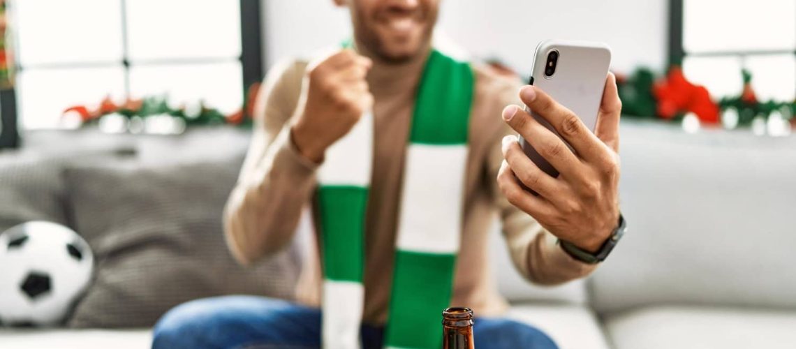 homem no celular ganhando na aposta esportiva