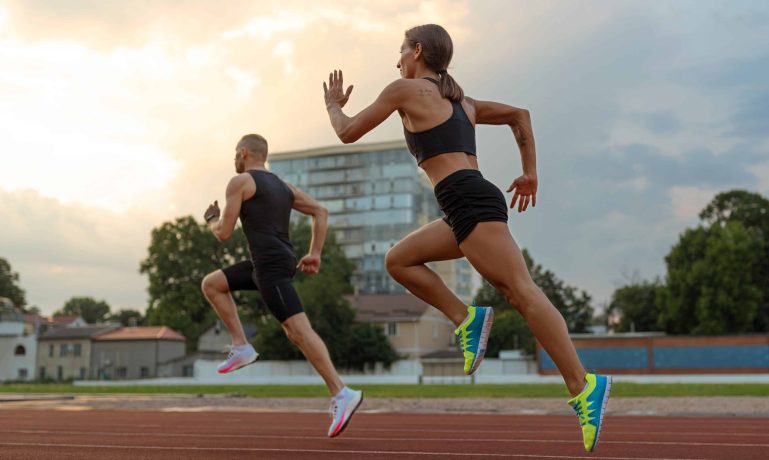 Imagem de dois atletas em uma corrida, representando o conceito de Bolsa Atleta, um programa que oferece apoio financeiro a esportistas. A cena simboliza o esforço e dedicação necessários para se qualificar para o benefício.