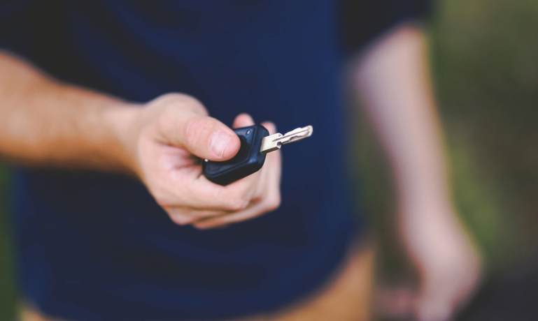 Homem segurando a chave do seu carro que teve o Licenciamento atrasado